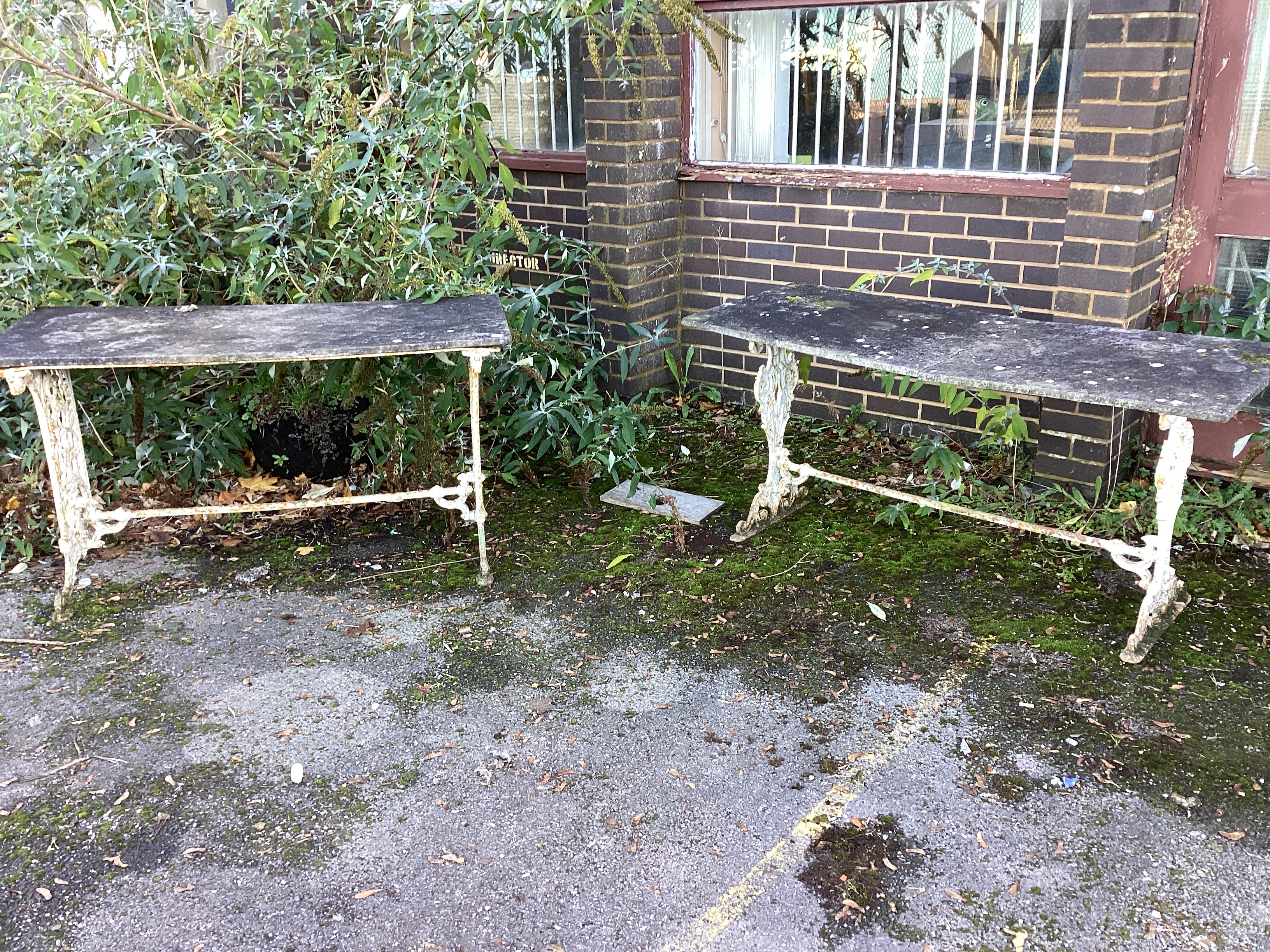 A Victorian painted cast iron garden table with weathered marble top, together with a similar table with damaged marble top, larger width 153cm, height 70cm.